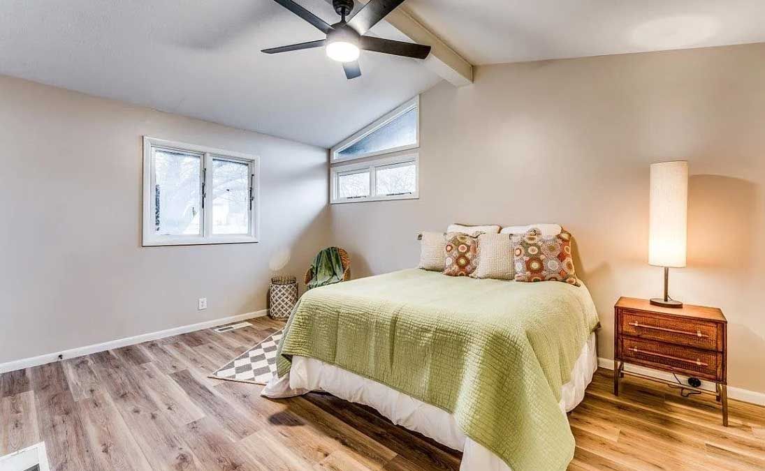 A bedroom with a bed , nightstand , lamp and ceiling fan.