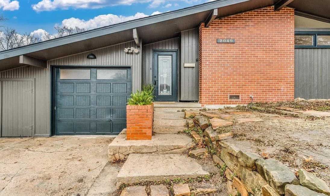 A brick house with a garage and stairs leading up to it.