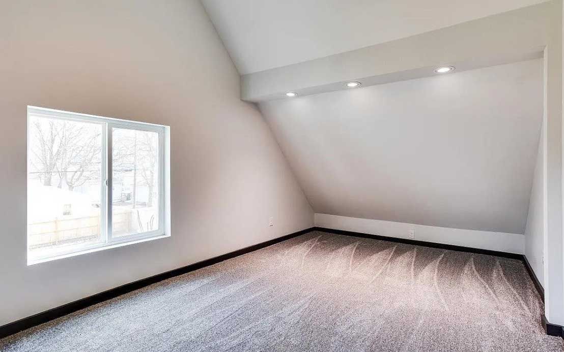 An empty room with a window and a carpeted floor.