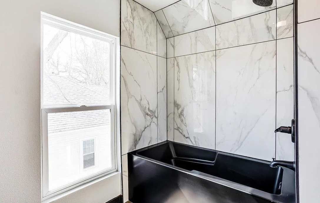 A bathroom with a black tub and a window.
