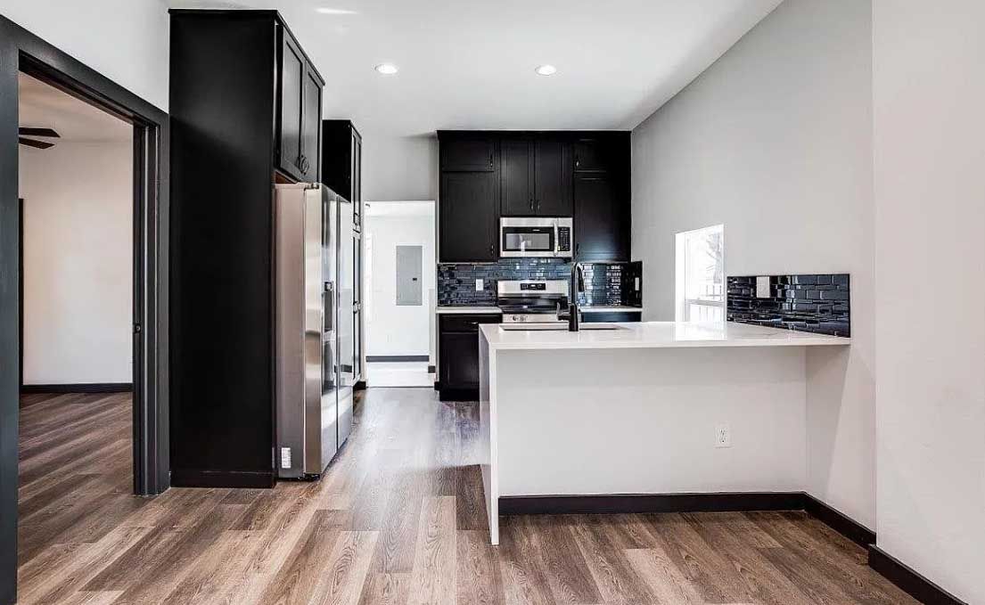 A kitchen in a house with black cabinets and stainless steel appliances.