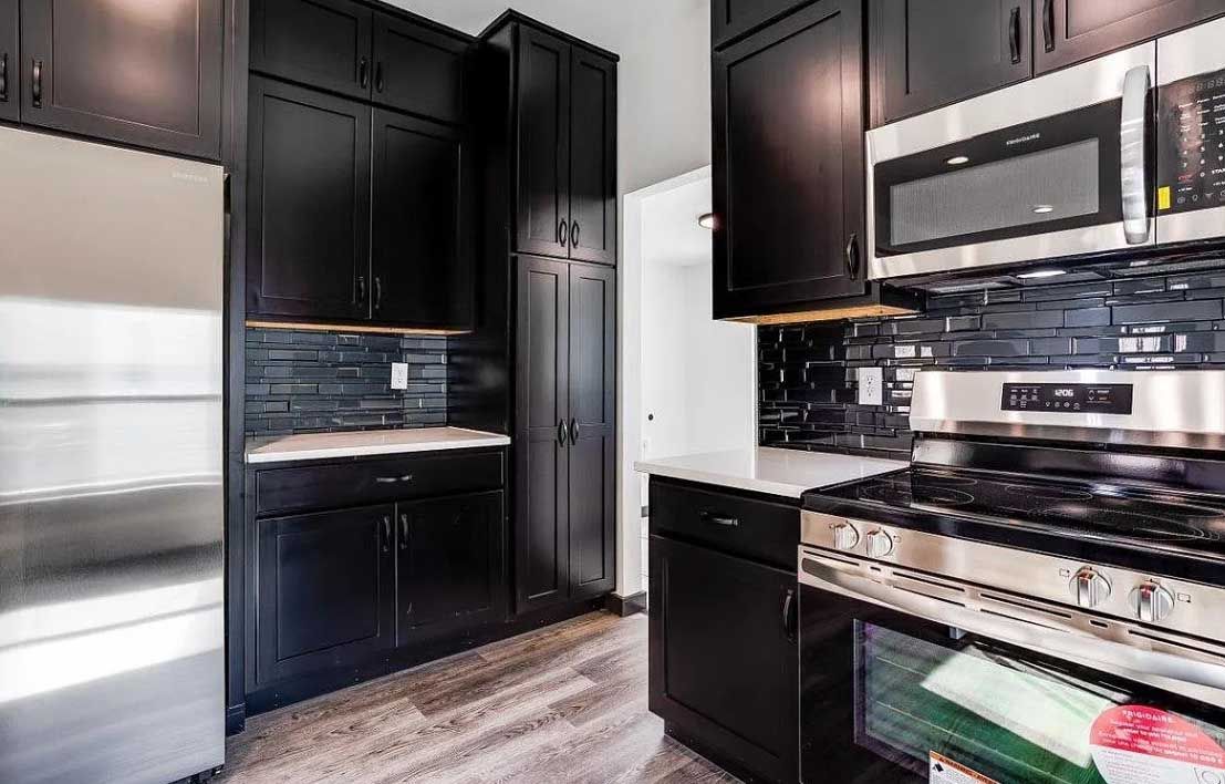 A kitchen with black cabinets and stainless steel appliances.