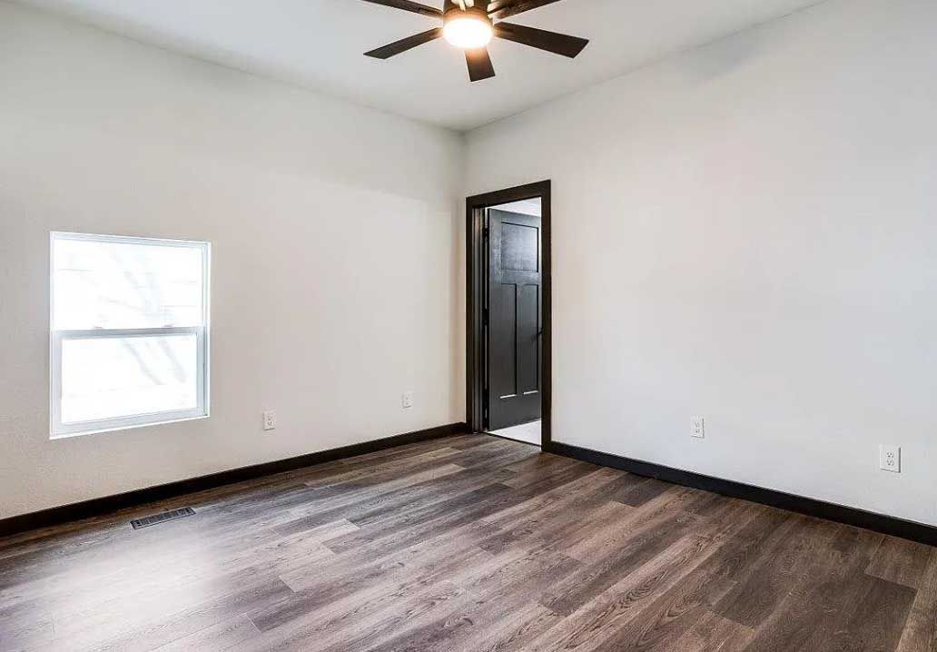 An empty room with hardwood floors and a ceiling fan.