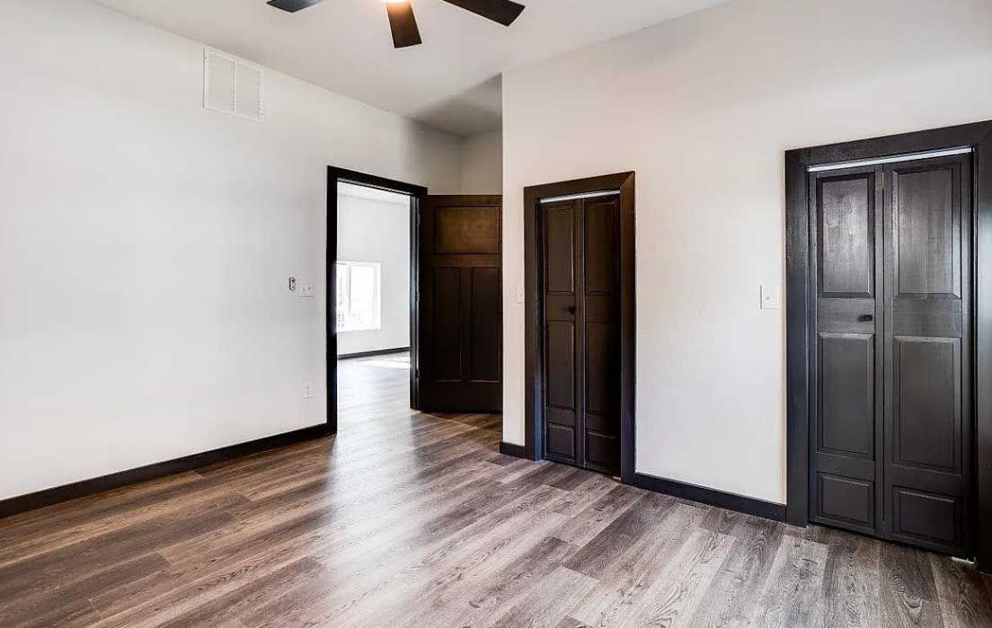 An empty room with hardwood floors and a ceiling fan.