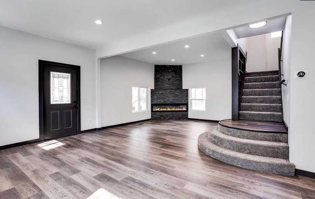 A living room with hardwood floors , stairs and a fireplace.