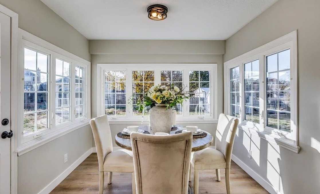 A dining room with a table and chairs and a large window.