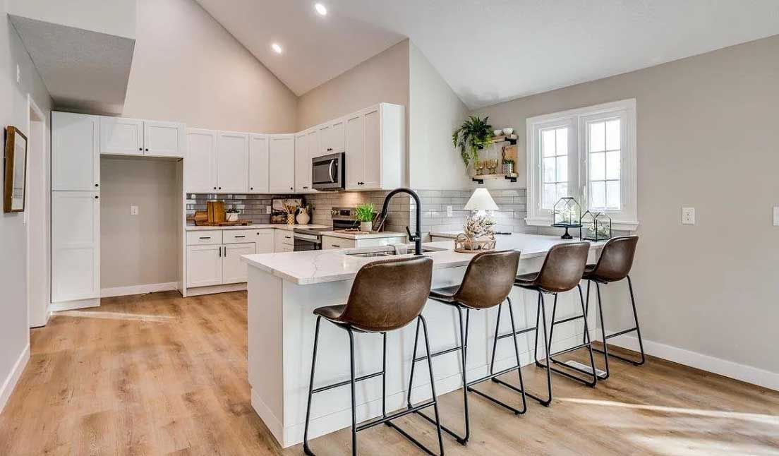 A kitchen with a large island and stools in it.