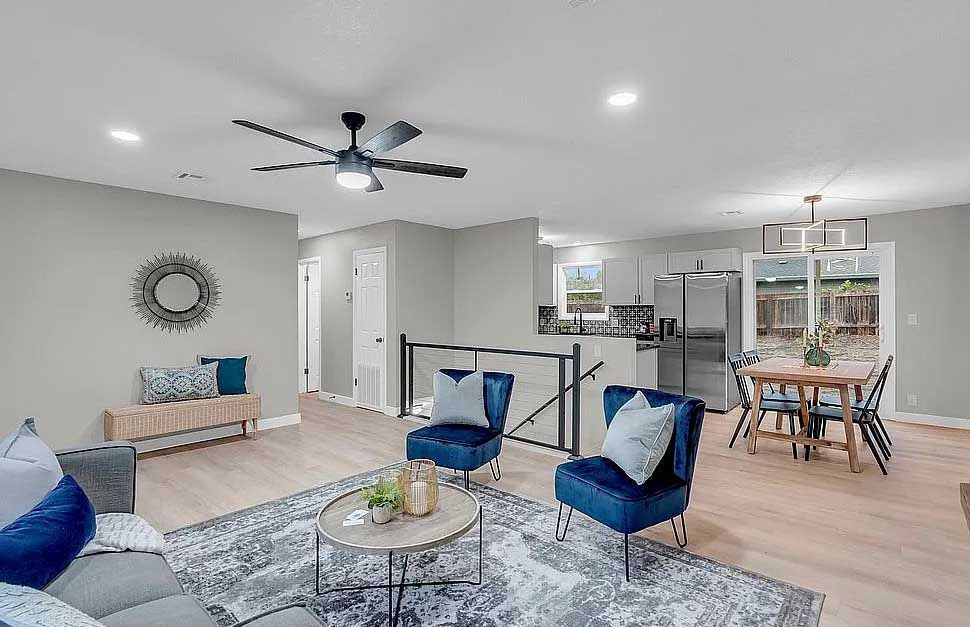 A living room with a couch , chairs , a table and a ceiling fan.