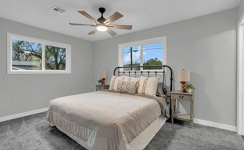 A bedroom with a bed and a ceiling fan.
