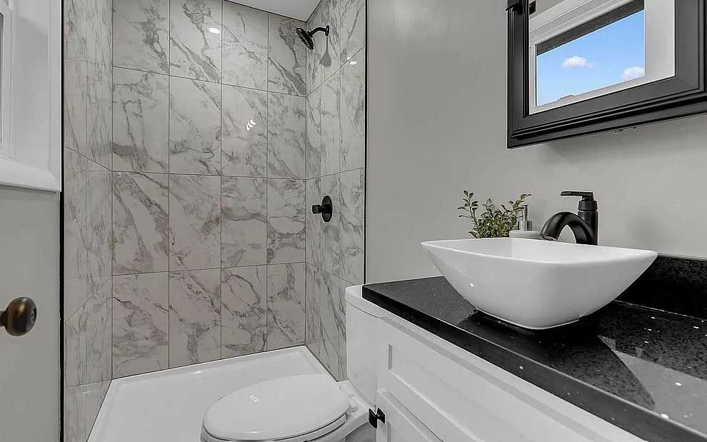 A bathroom with a toilet , sink , mirror and shower.