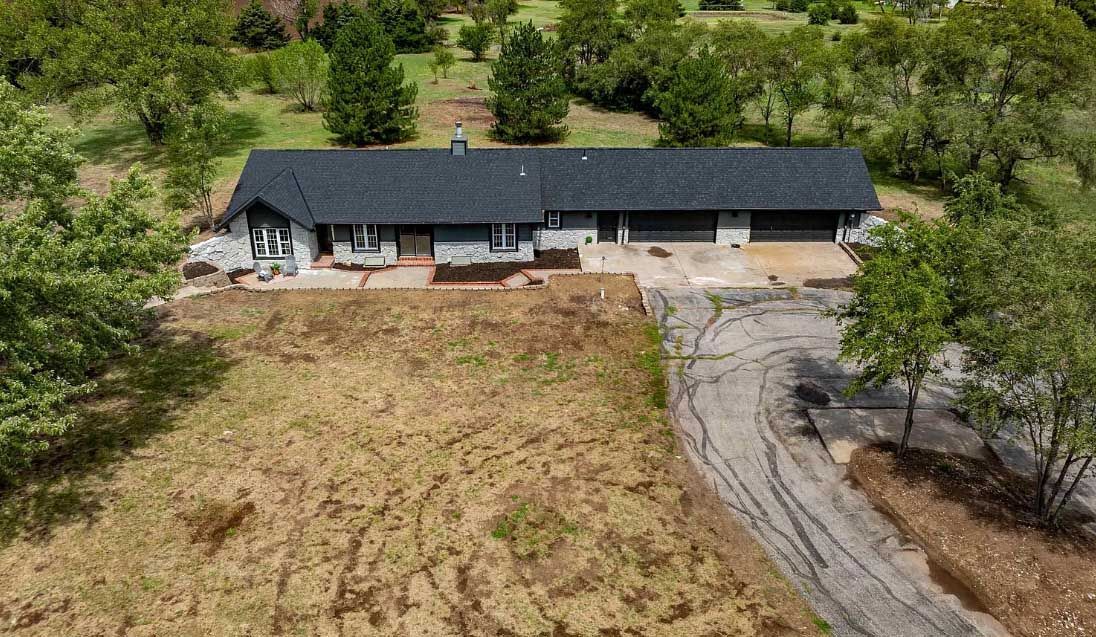 An aerial view of a house in the middle of a field surrounded by trees.