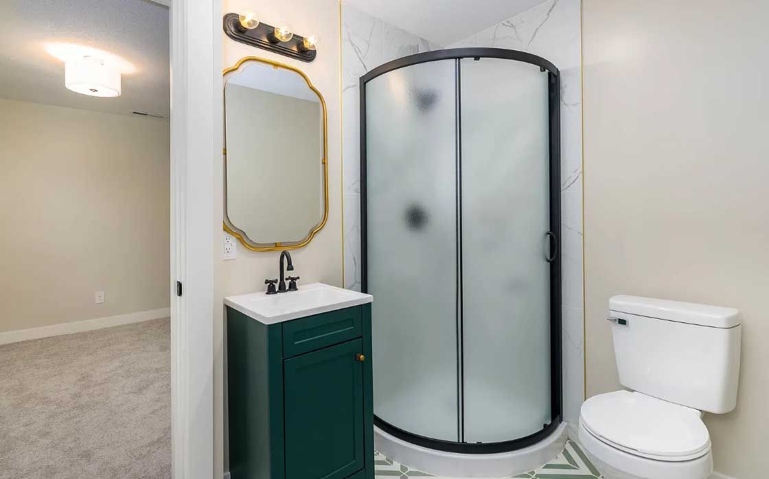 A bathroom with a toilet , sink , shower and mirror.