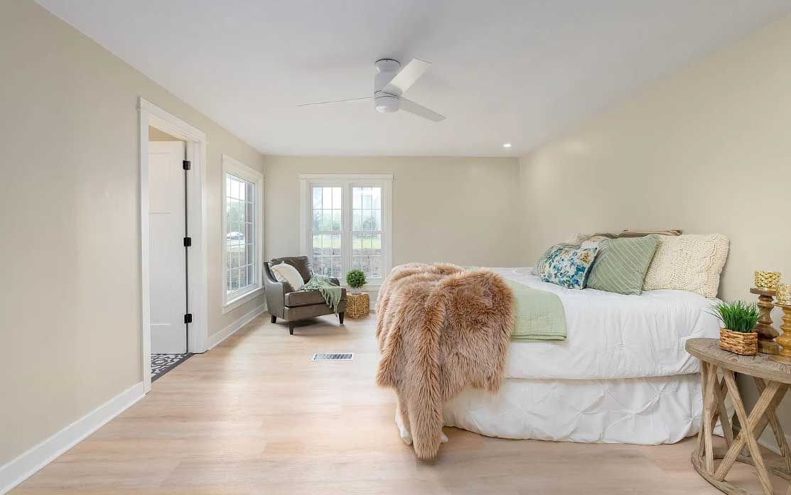 A bedroom with a large bed and a ceiling fan.
