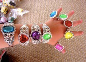 A child is wearing a bracelet and rings on her wrist.