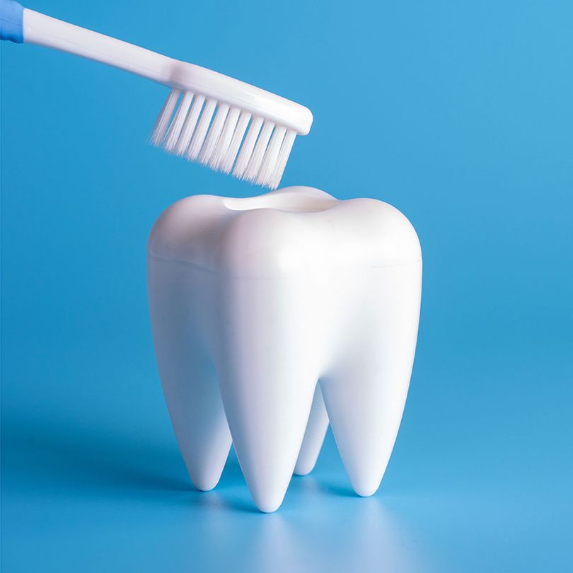 A tooth is being cleaned with a toothbrush on a blue background.