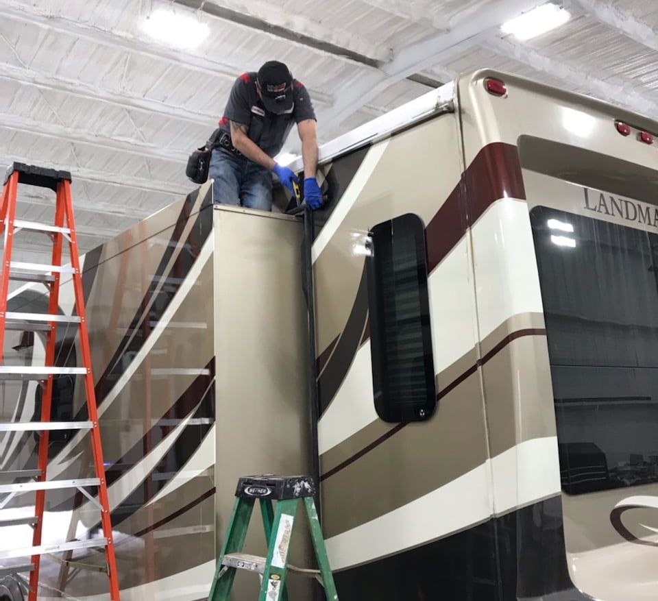 A man is working on the side of a rv.