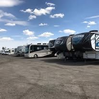 A row of recreational vehicles are parked in a parking lot.