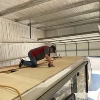 A man is kneeling on the roof of a rv.