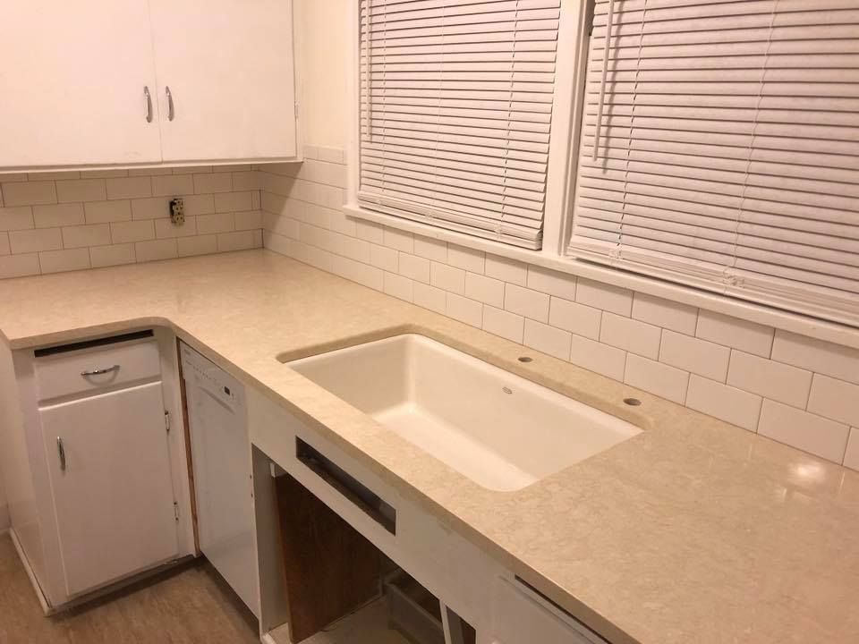 Kitchen remodel with beige countertop, white cabinets, and subway tile backsplash.
