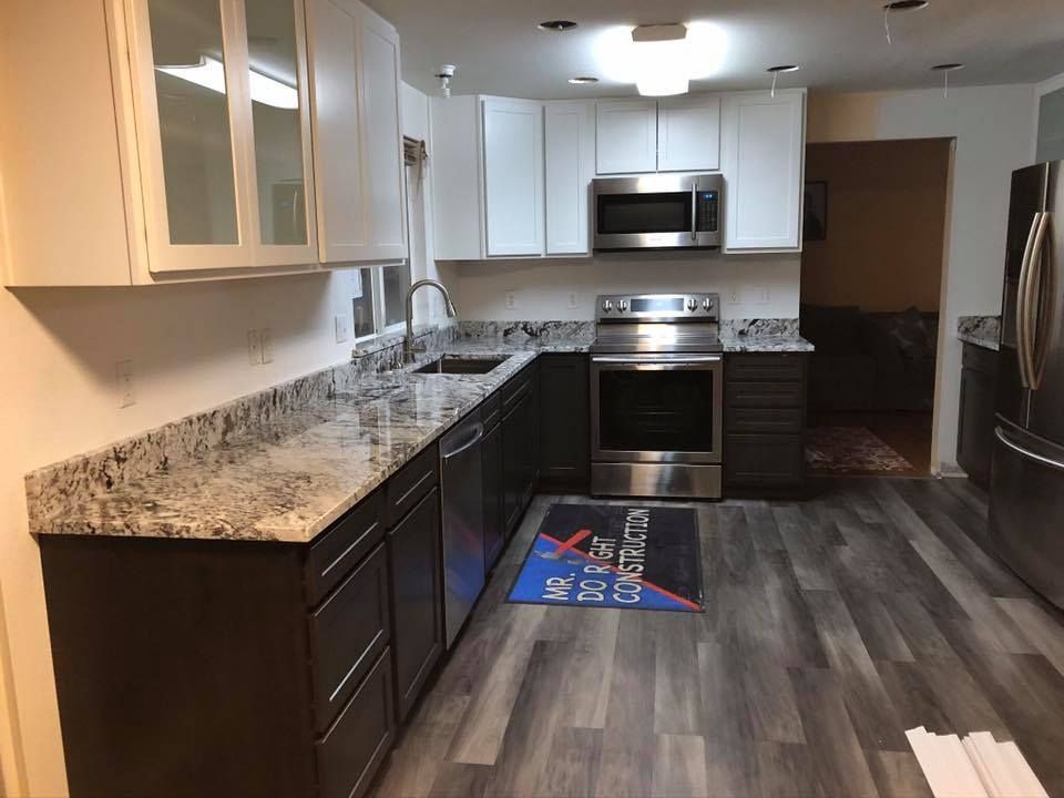 Modern kitchen with white and dark brown cabinets, granite countertops, and stainless steel appliances.