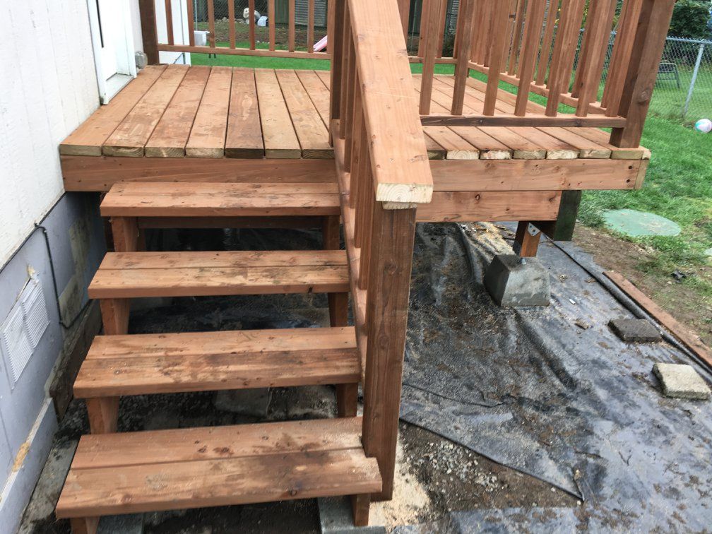 Wooden deck with stairs leading to ground level. Brown wood, weathered look.