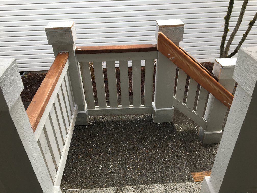 Wooden stair railings with white vertical slats and brown handrails. Entryway.