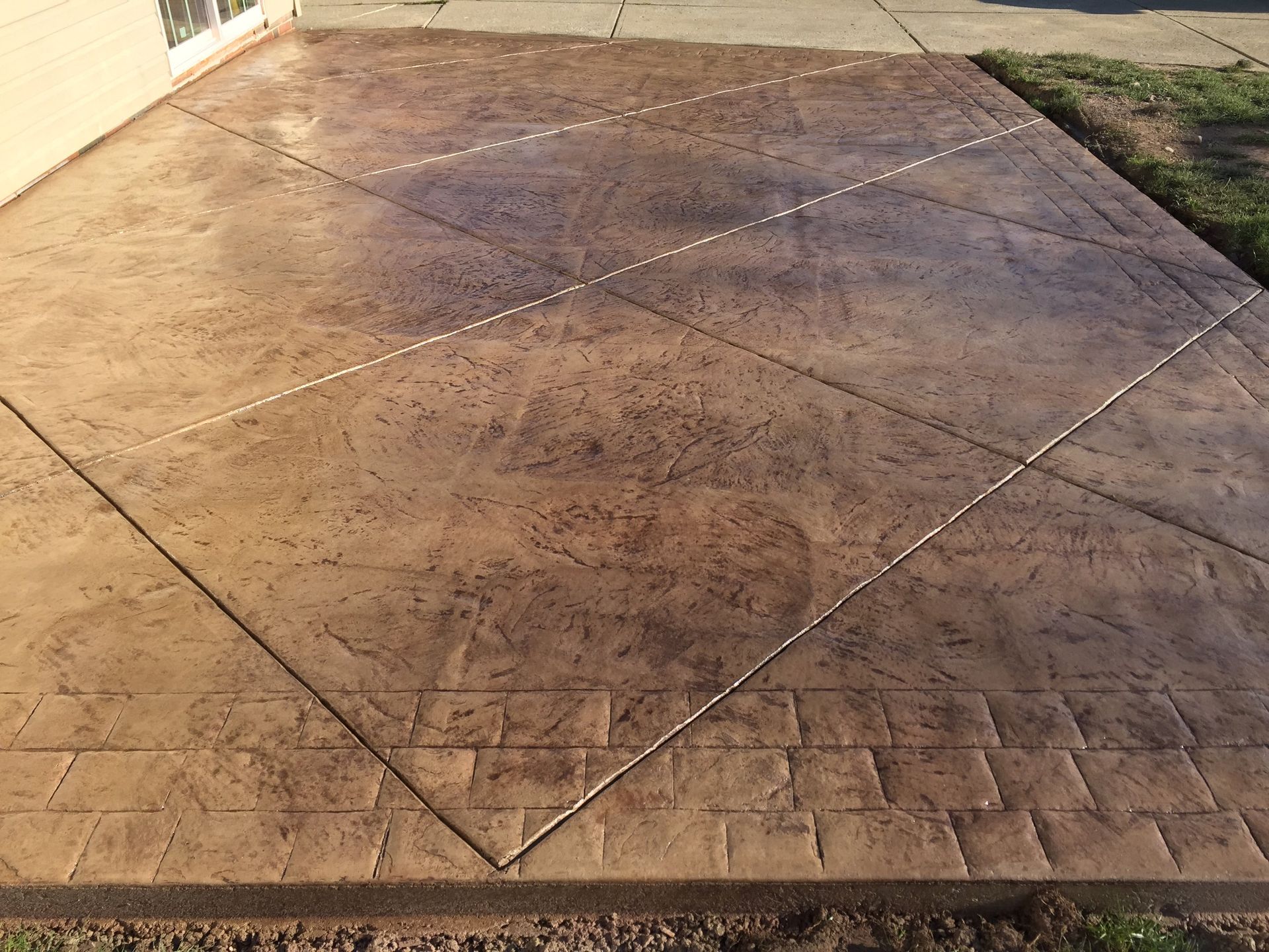 A concrete patio with a brick pattern on it.