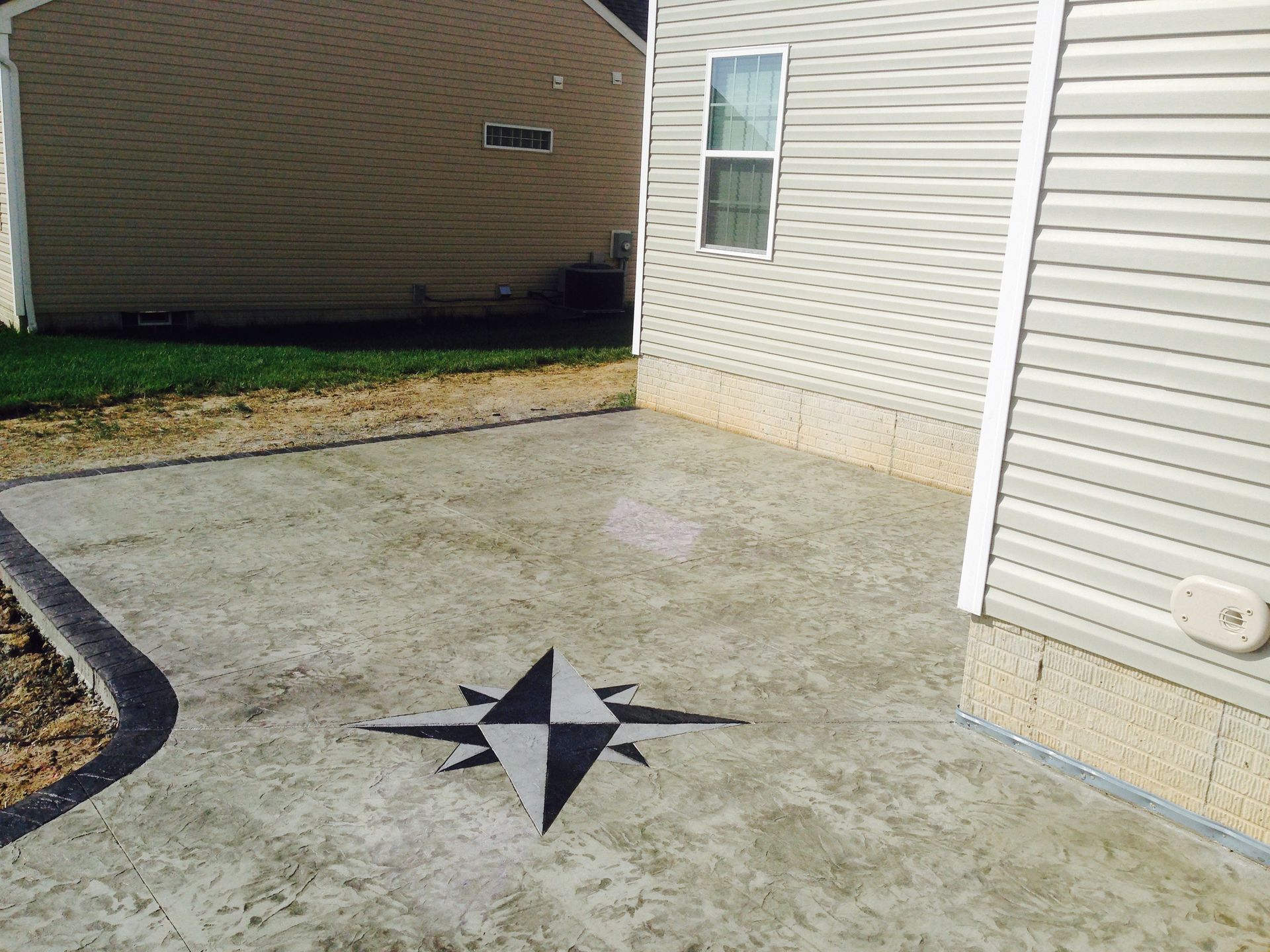 A concrete patio with a compass on it in front of a house