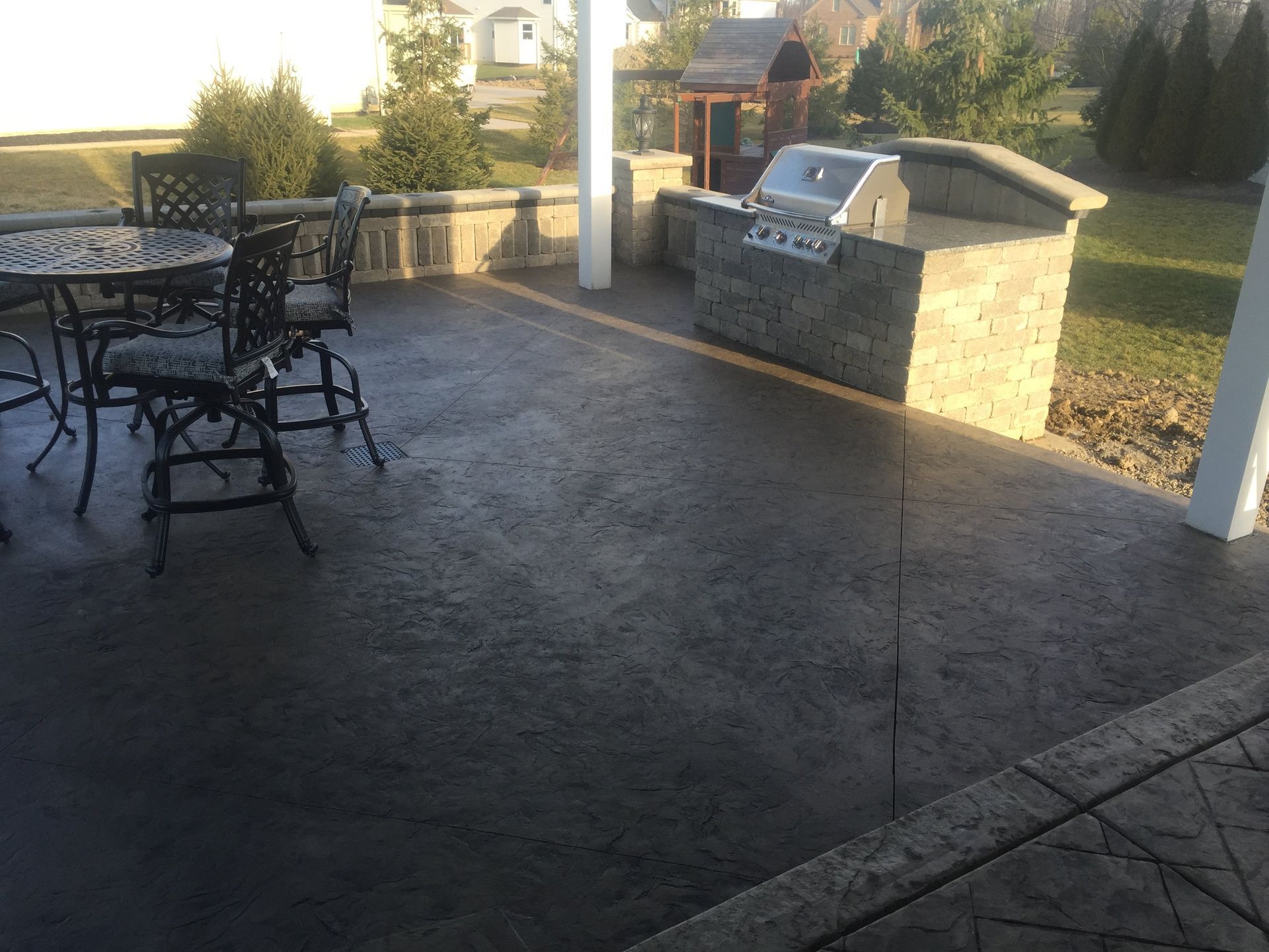 A patio with a table and chairs and a grill
