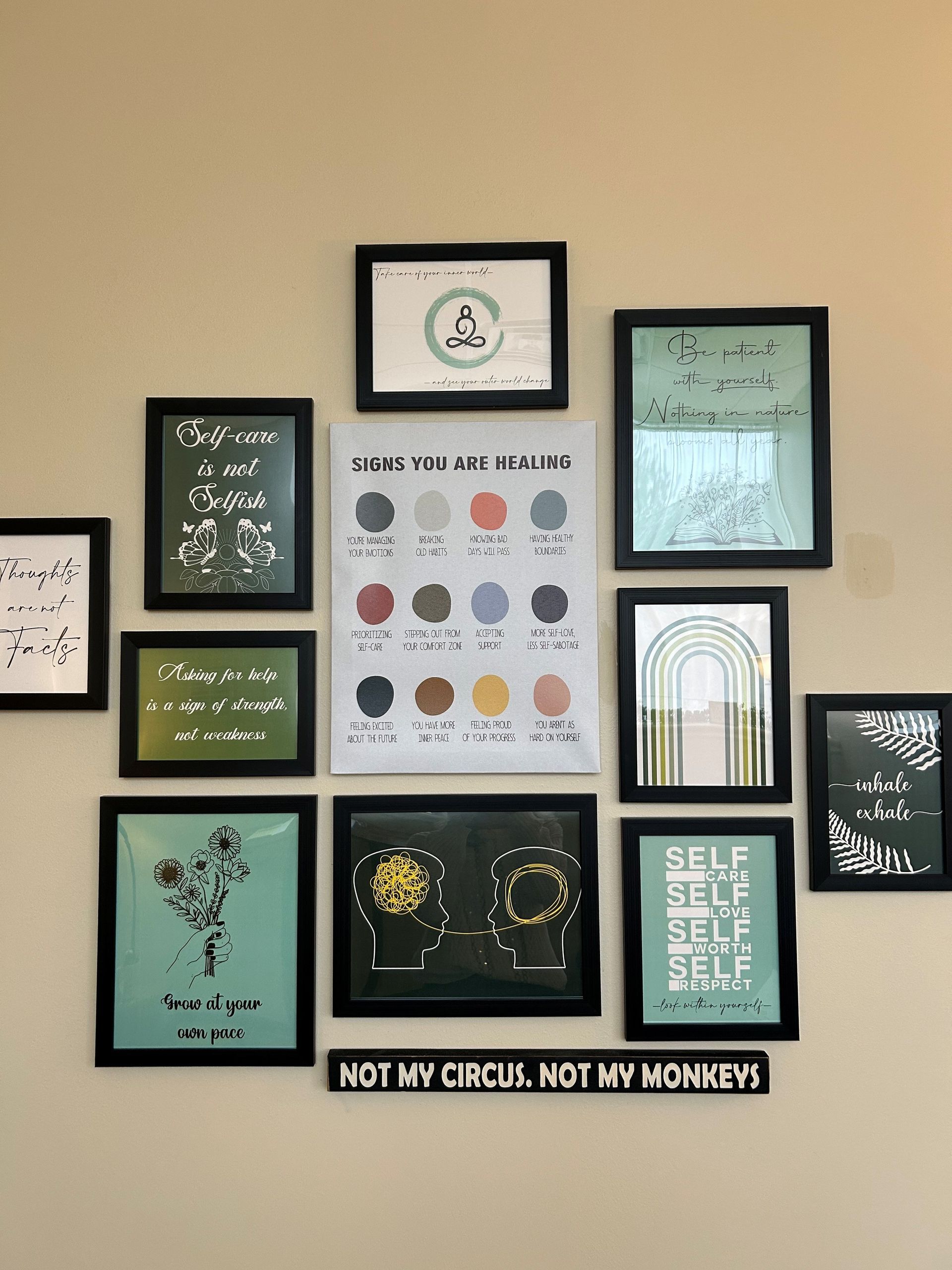 A wall filled with framed pictures and a sign that says not my circus not my monkeys.