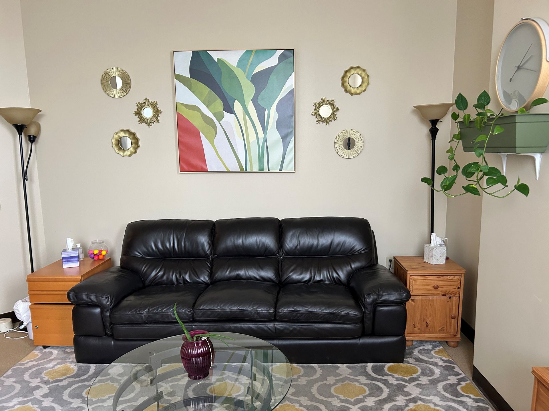A living room with a black leather couch and a glass coffee table.