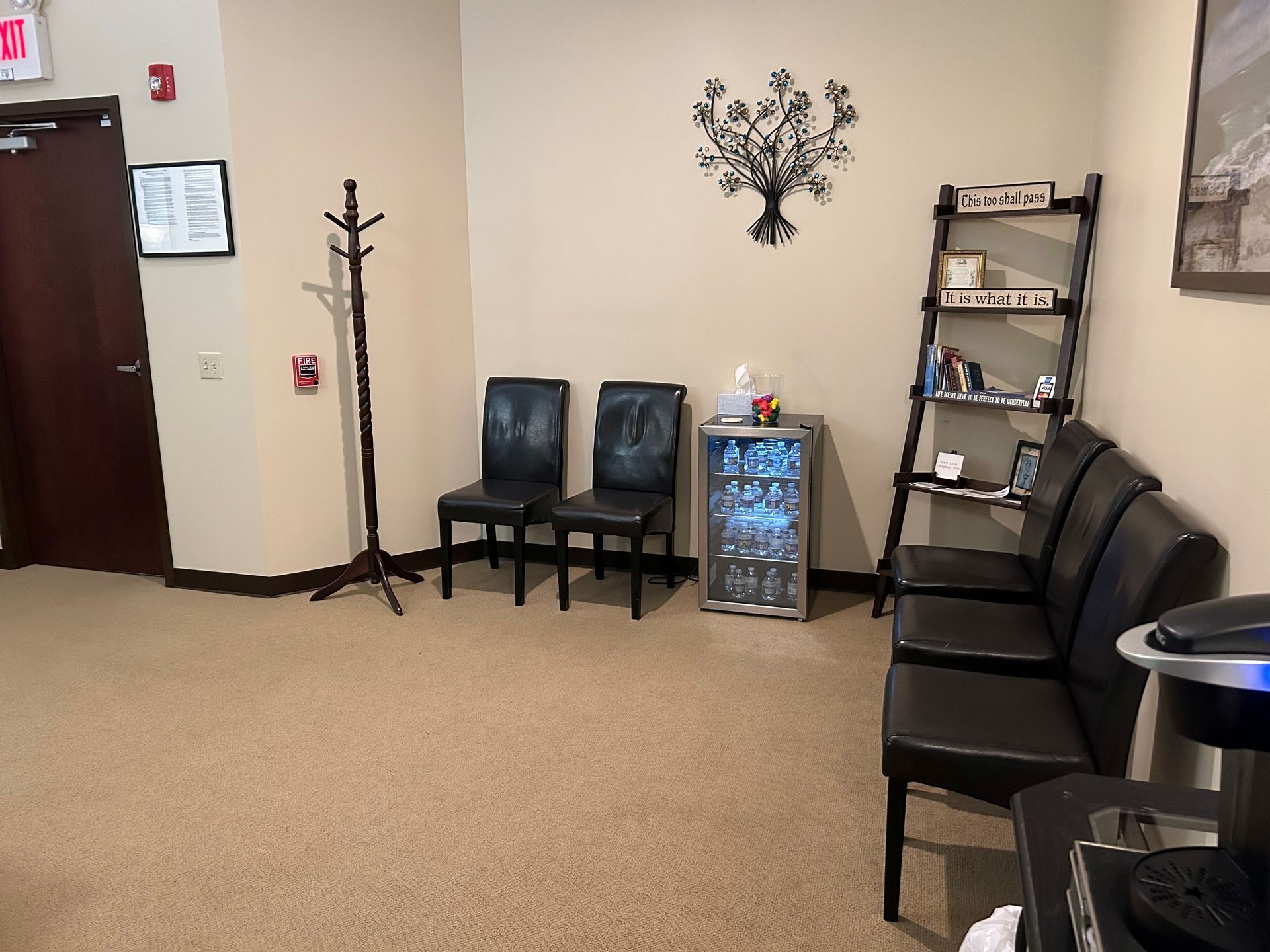A waiting room with a row of chairs and a refrigerator.
