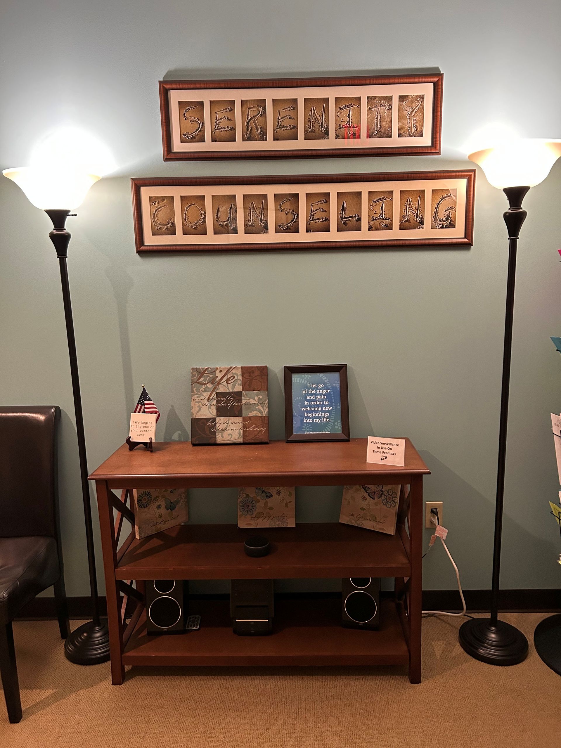 A living room with a wooden table, lamps, pictures on the wall, and a chair.