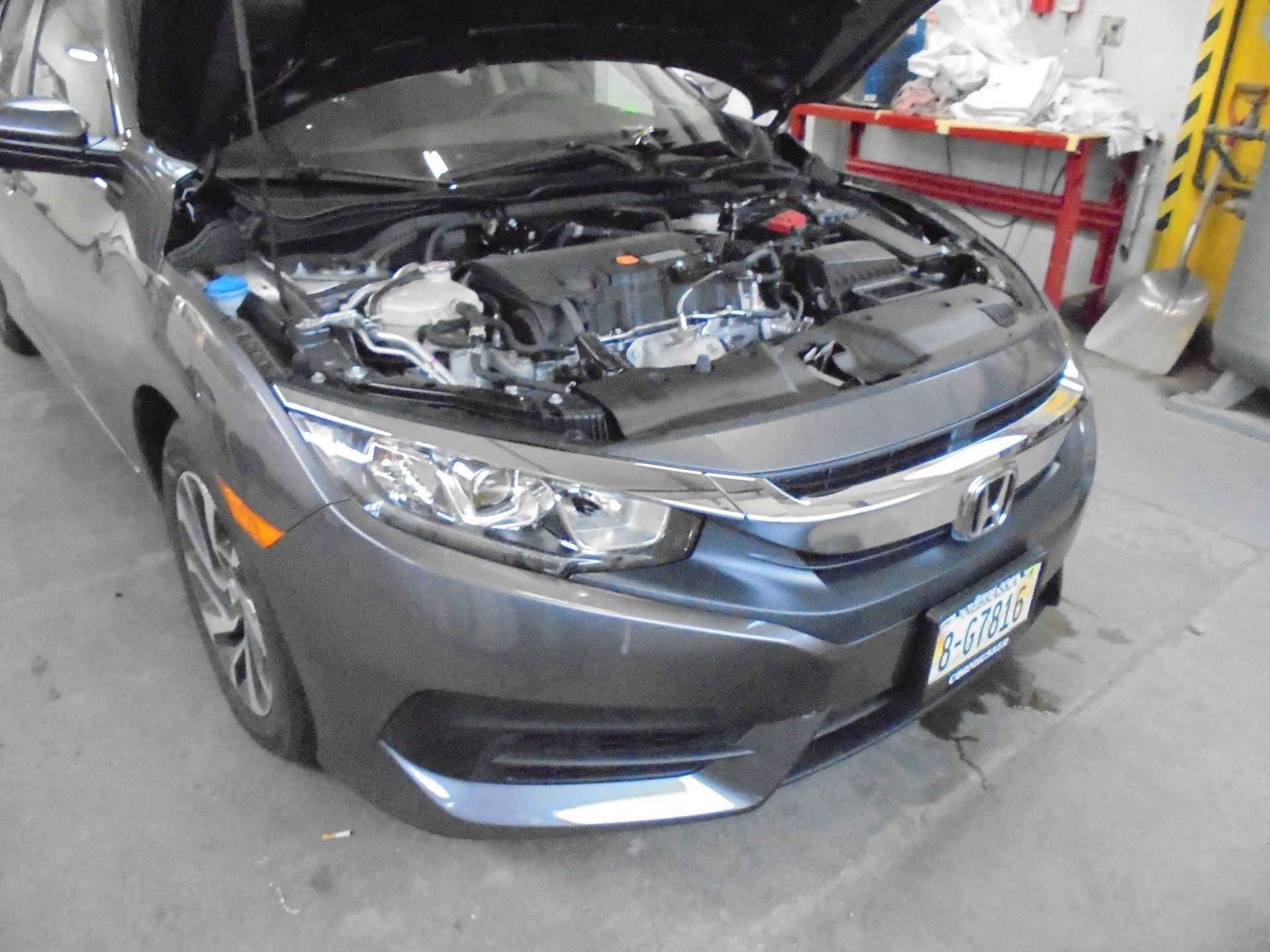 Gray Honda Civic with hood open, parked indoors.