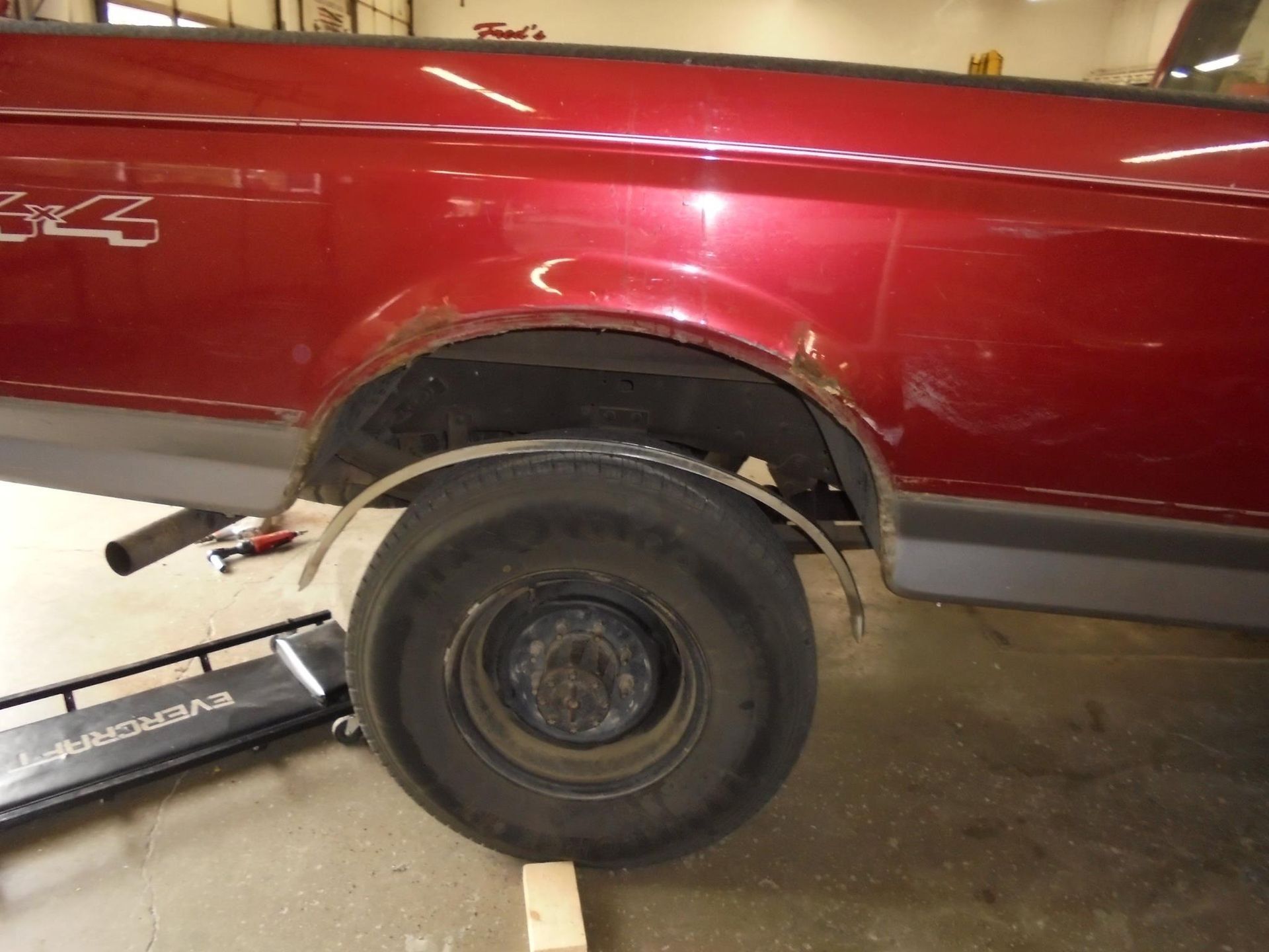 Red pickup truck with rusty wheel well and aftermarket fender.