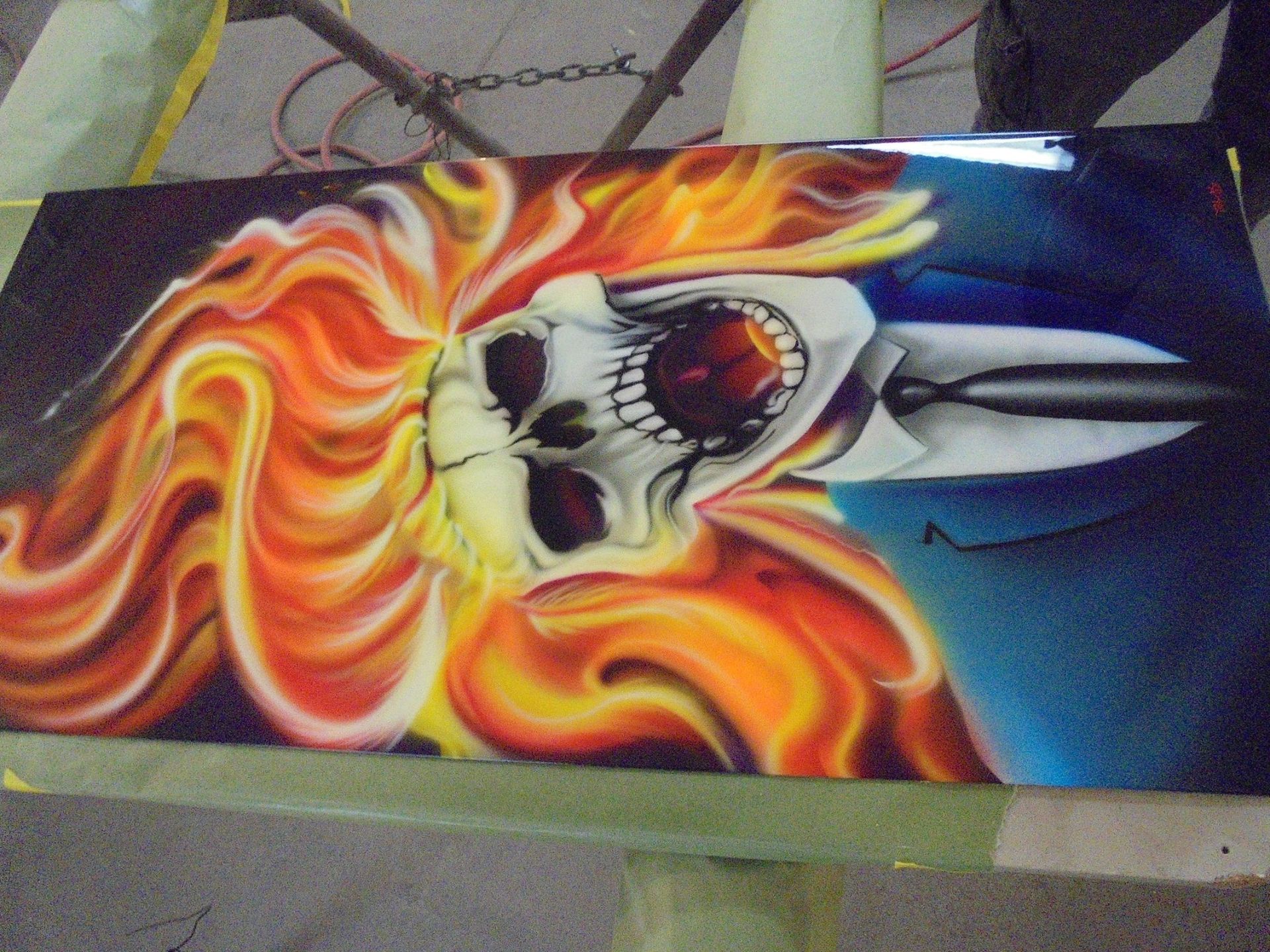 Skull engulfed in flames, piercing through a dark blue background with a silver spear.