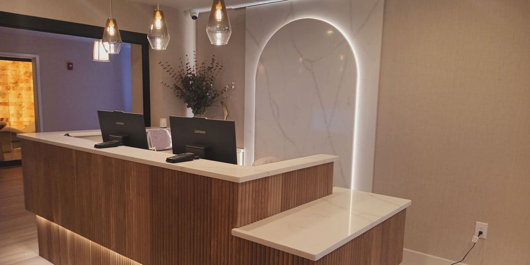 Reception desk in a spa or office, with computers, wood paneling, and a glowing arch.
