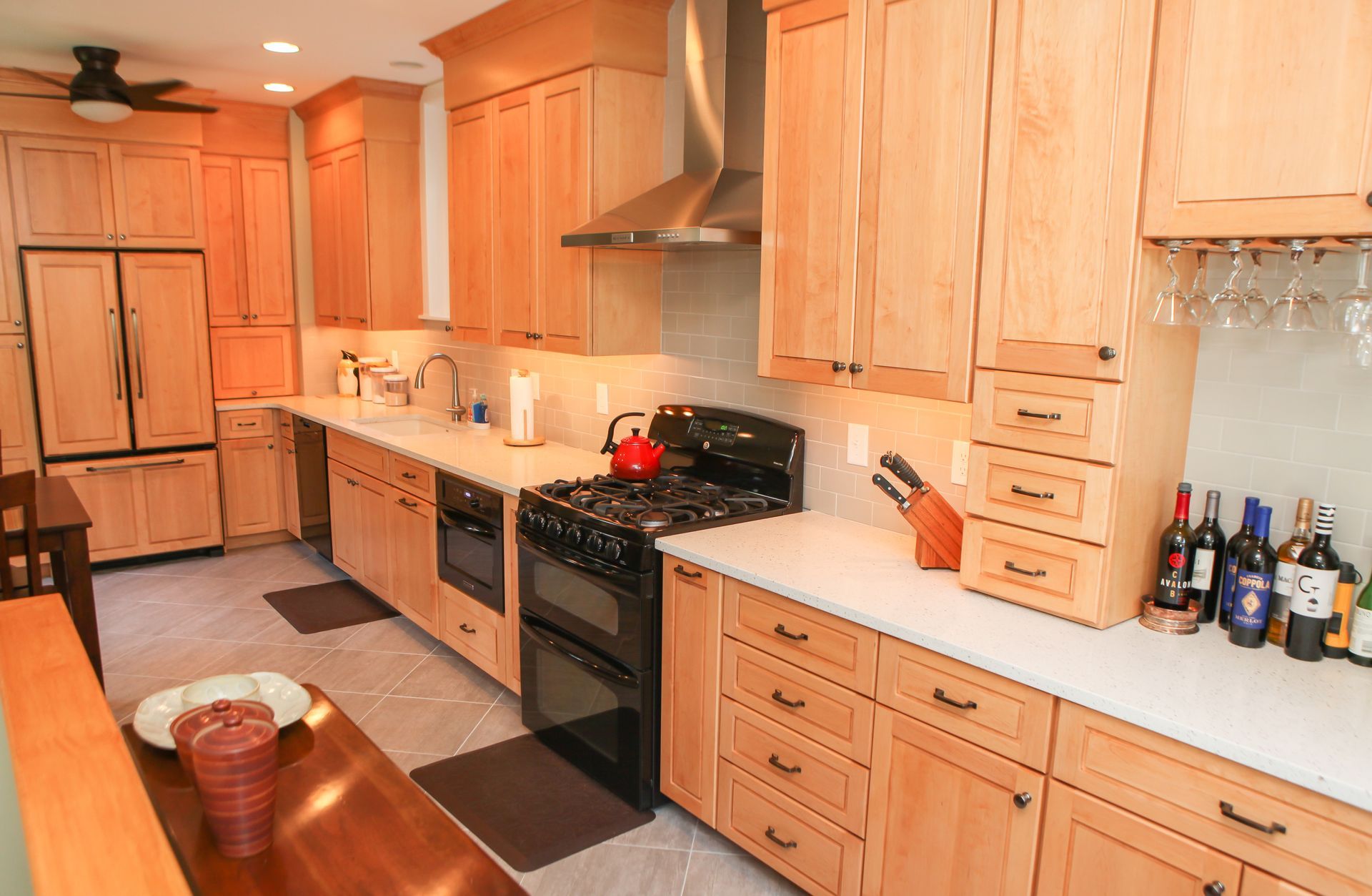 Kitchen with light wood cabinets, stainless steel appliances, white countertops, and a dining table.