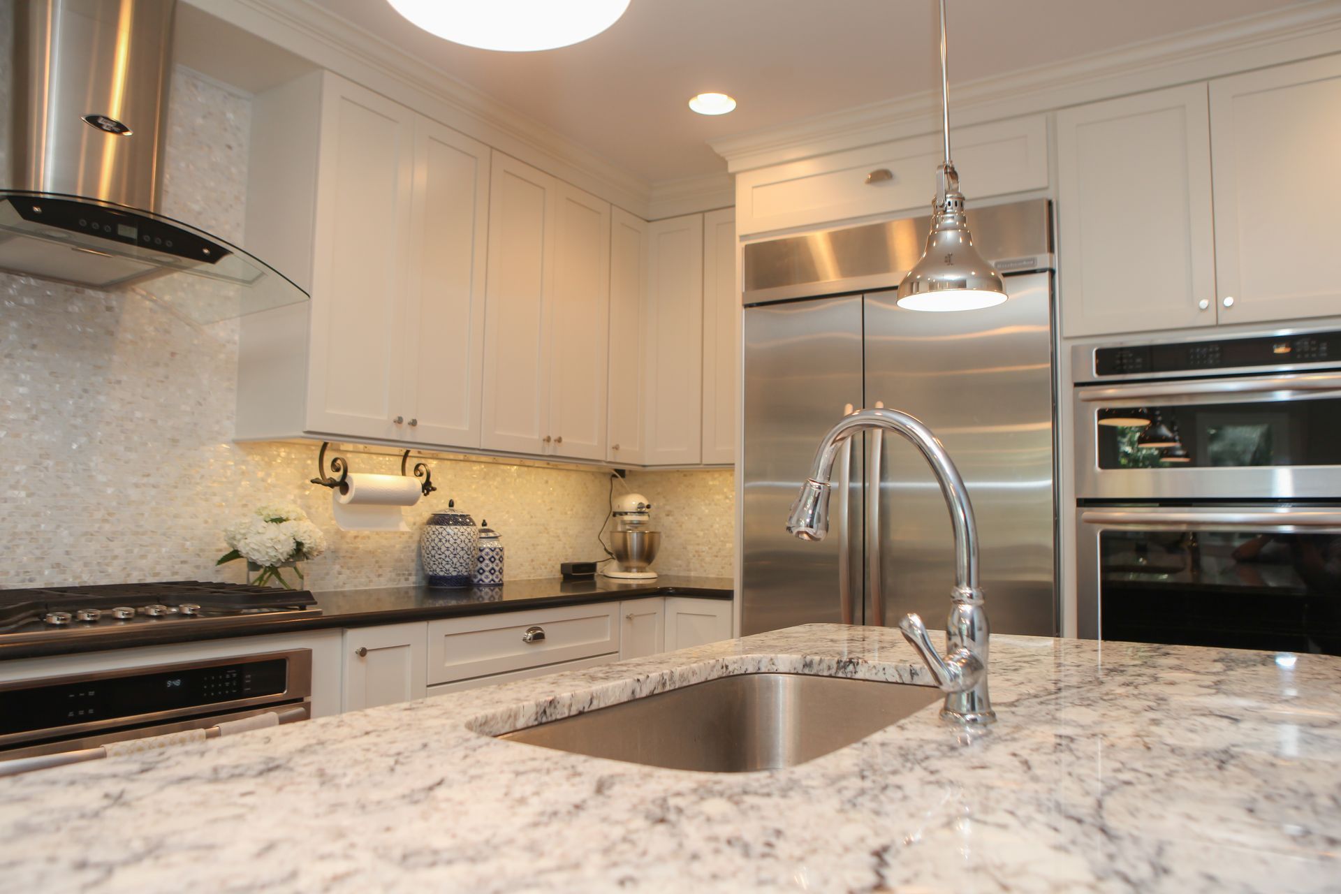 Modern kitchen with white cabinets, stainless steel appliances, granite countertops, and a large sink.