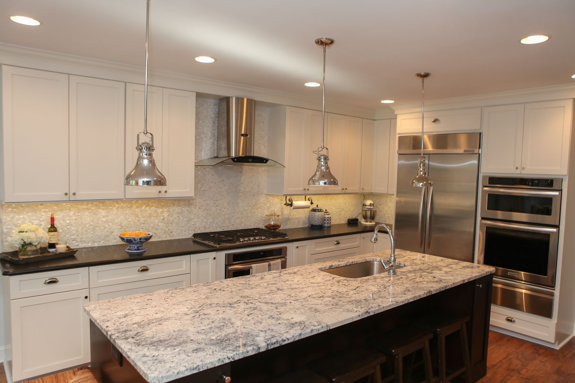 Modern kitchen with white cabinets, stainless steel appliances, and a granite island.