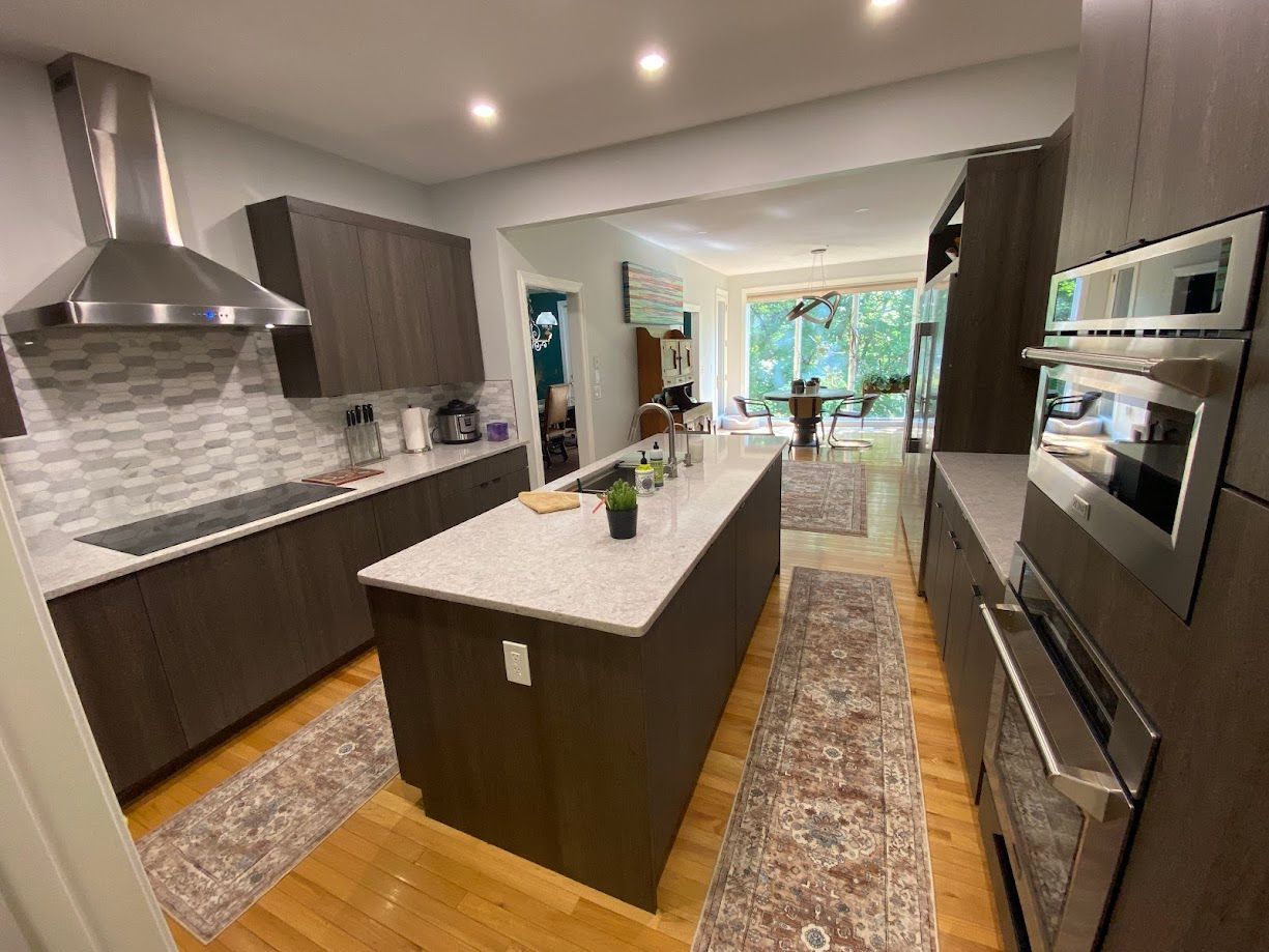 Modern kitchen with dark brown cabinets, island, and stainless steel appliances.