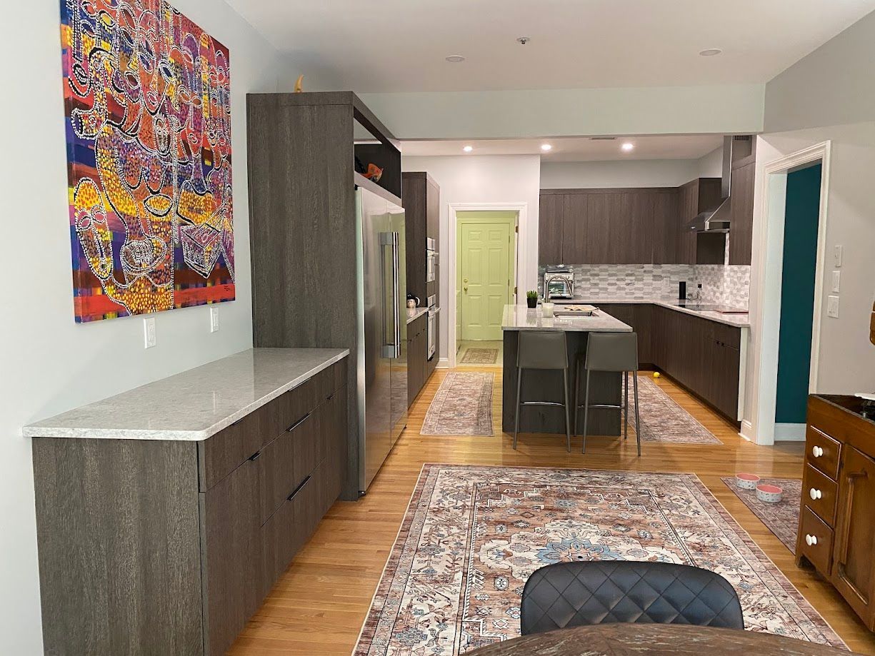 Modern kitchen with dark wood cabinets, a granite countertop, and colorful artwork.