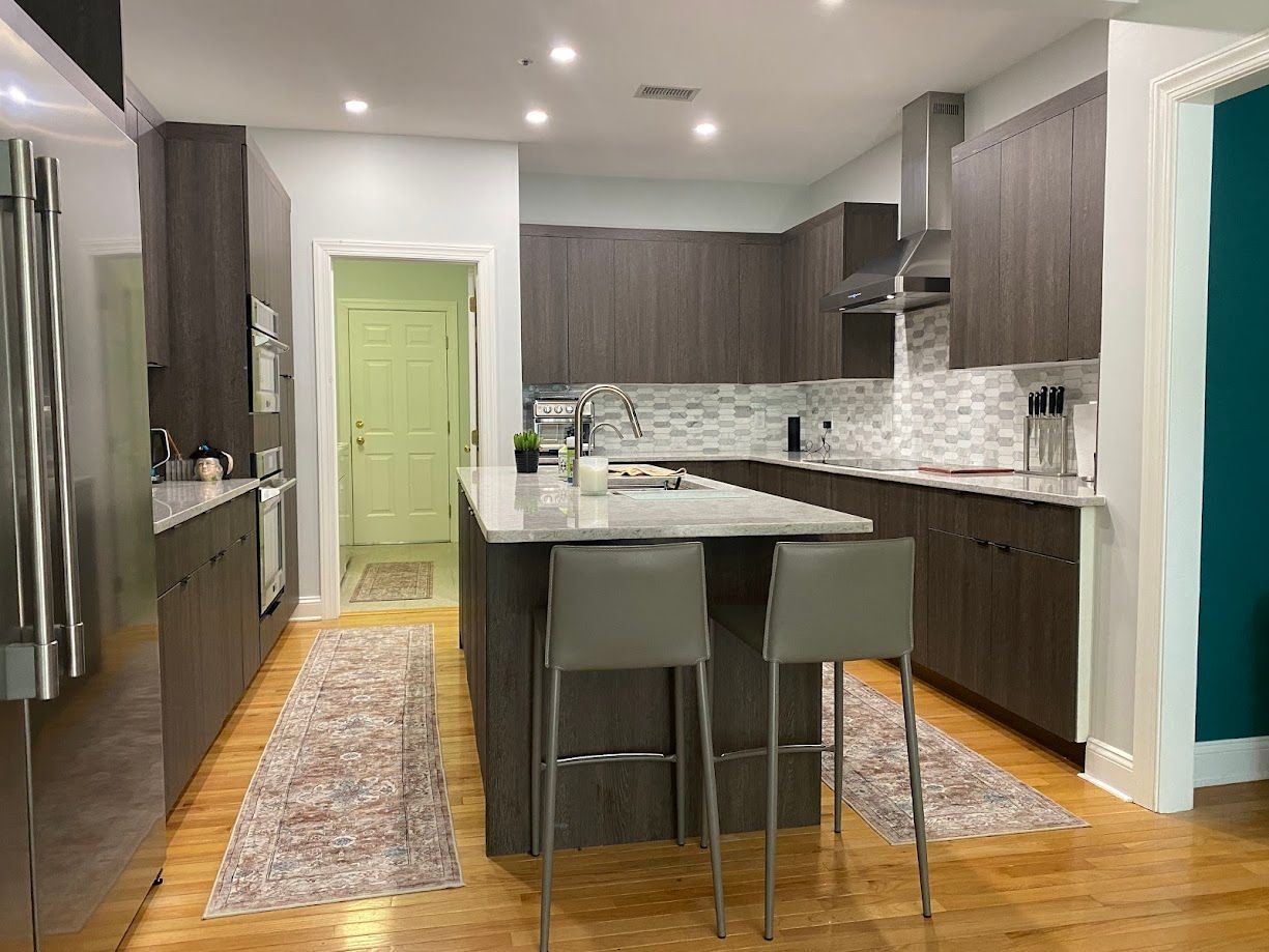 Modern kitchen with gray cabinets, island with stools, and light wood floors.