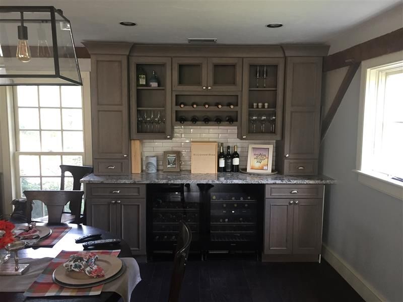 Built-in gray cabinetry with wine storage and bar area; a dining room setting.