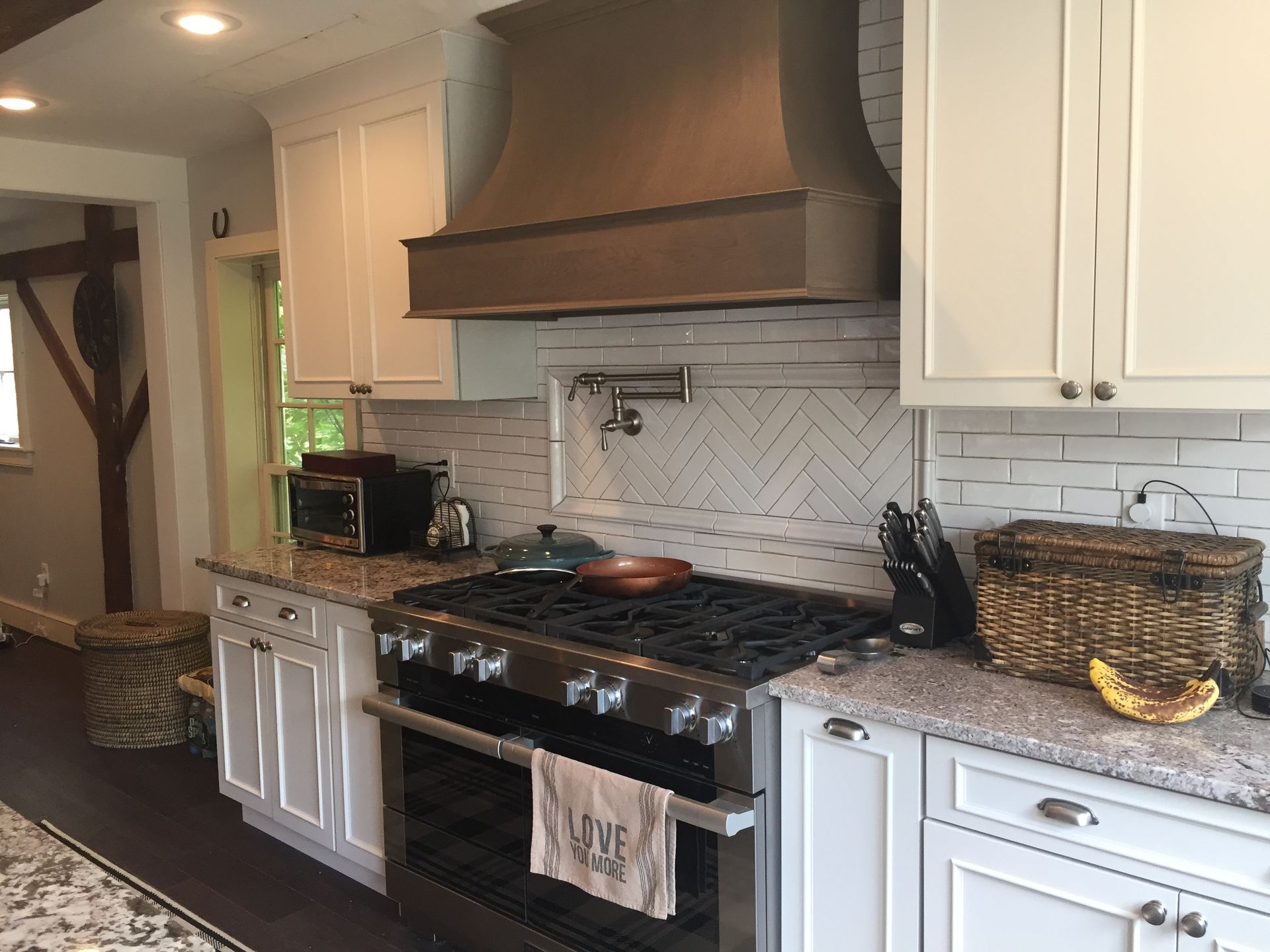 Kitchen with stainless steel stove, white cabinets, brown range hood, and light-colored countertops.