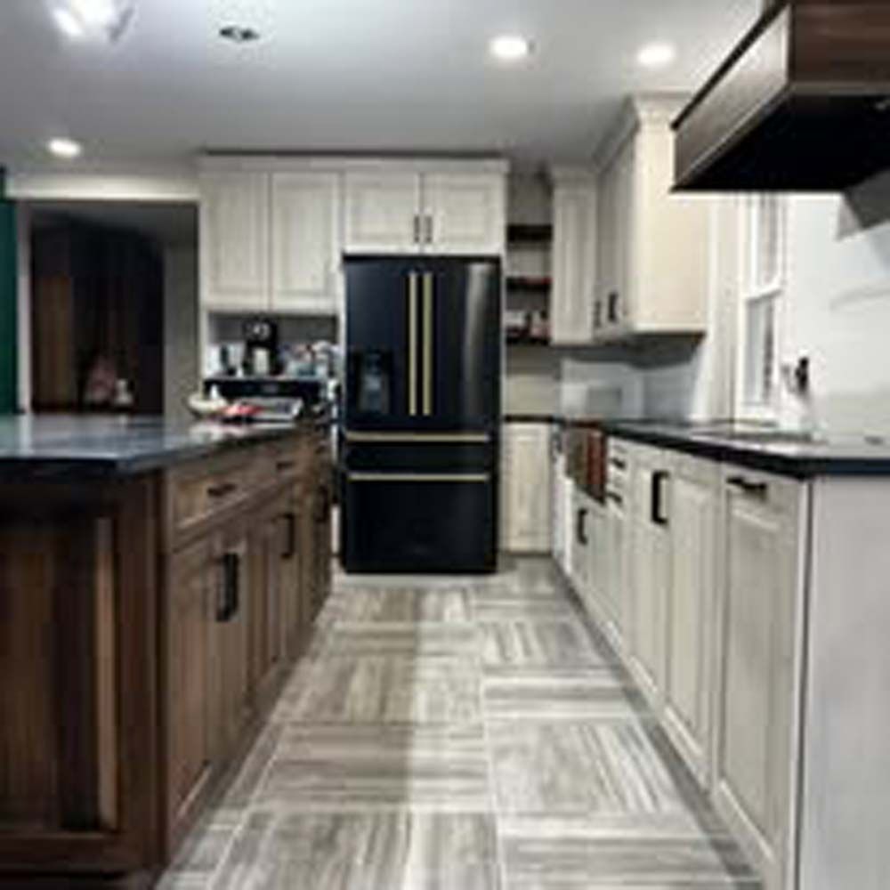 Kitchen with black fridge, two-toned cabinets, and island with dark wood.