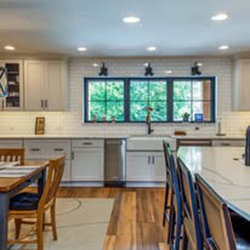 Kitchen with cabinets, island, and large window overlooking a lush outdoor view.