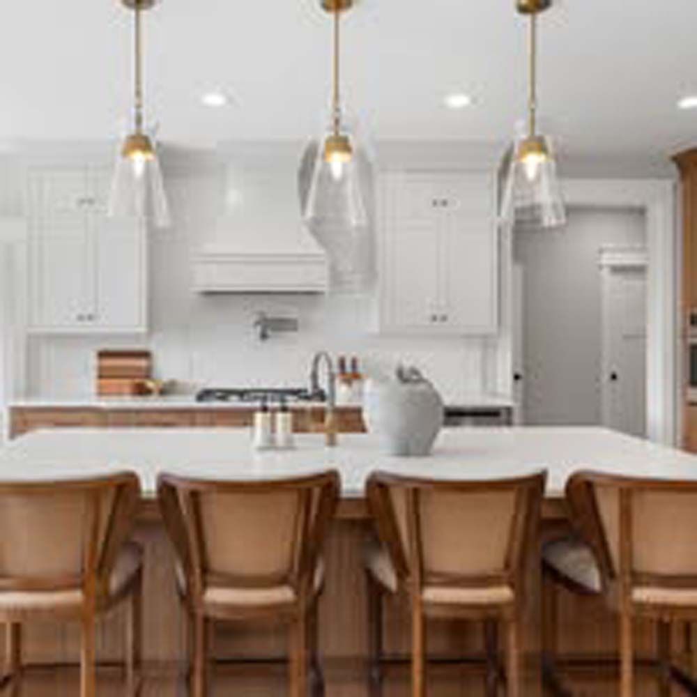 Kitchen with white cabinets, wooden island, pendant lights, and chairs.
