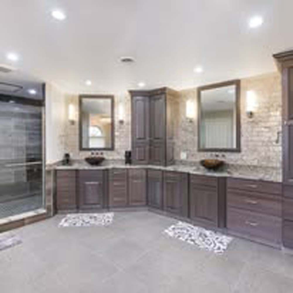 Bathroom with double vanity, two mirrors, and stone accent wall.