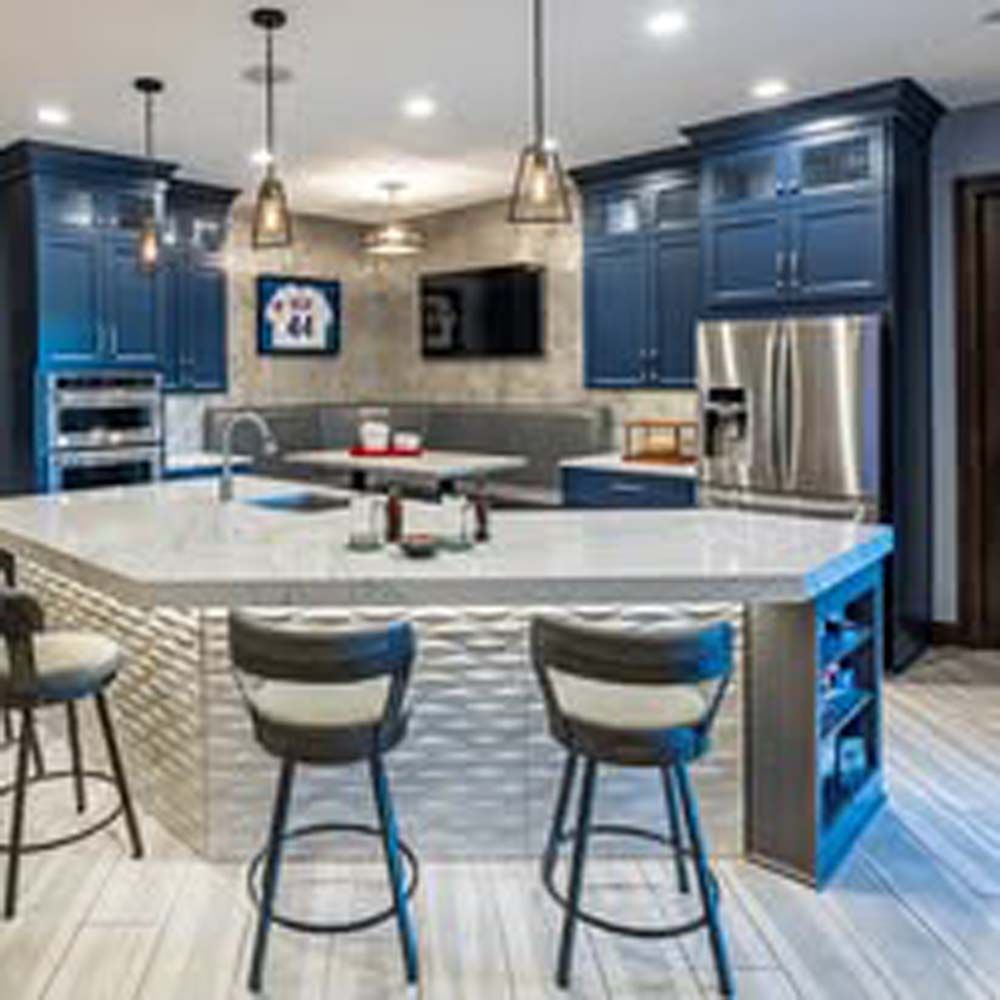 Modern kitchen with blue cabinets, an island with bar stools, and stainless steel appliances.